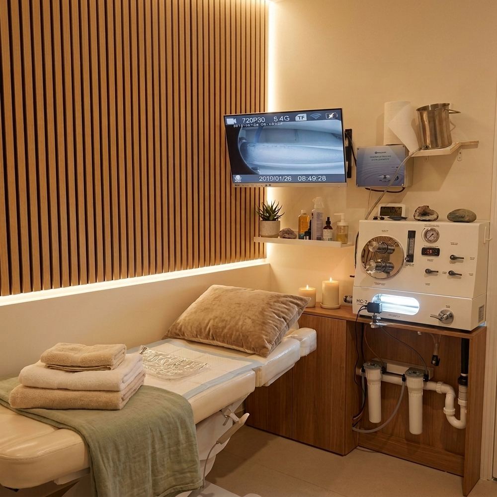A private treatment room at the Bella Vista clinic: warm timber slat wall, soft lighting, candles, folded towels and a treatment bed.